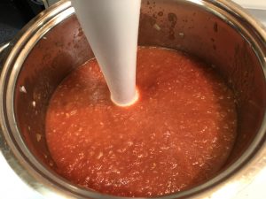 Tomato pesto sauce being blended with immersion blender