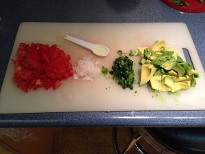 cutting board with chopped tomato, onion, jalapeño and avocado