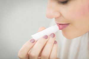 woman applying lip balm from tube