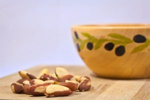 Brazil nuts on cutting board beside bowl