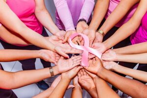 9 pairs of hand join together to hold a pink ribbon
