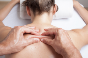 Woman face down on massage table, hands on her back doing myofascial release