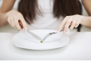 Woman eating one pea on a plate