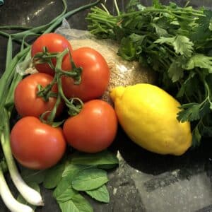 Tomato, green onion, lemon, parsley, mint on a counter top