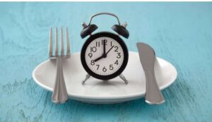 plate with an alarm clock with dials showing 8:00 and a fork and knife