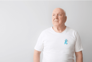 Older man with white shirt and blue ribbon over his heart.