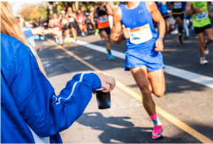 Man in race being handed a drink as he runs by